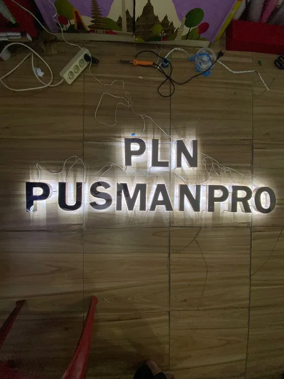 Huruf timbul backlight plat stainless dengan efek halo di belakang huruf.